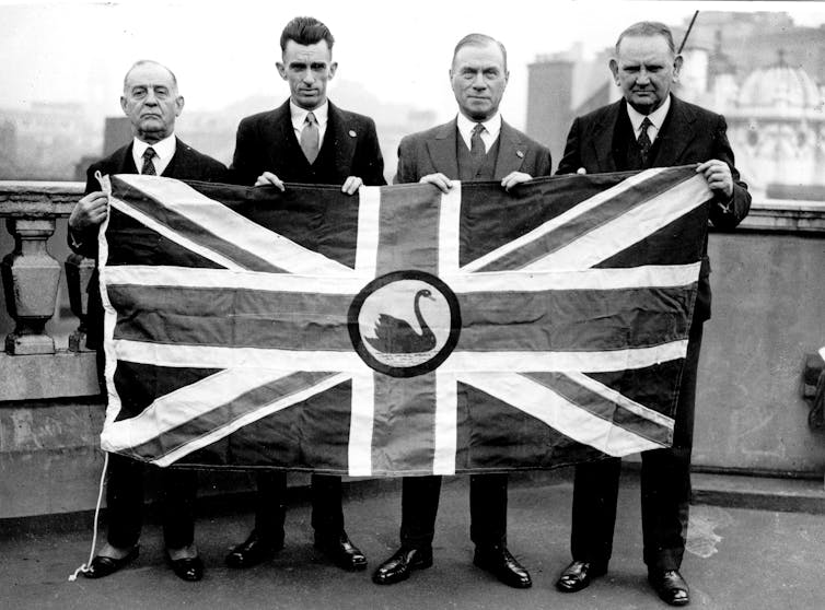 Four secessionist delegates hold the proposed flag for Western Australia on the roof of the Savoy House, Oct. 1934