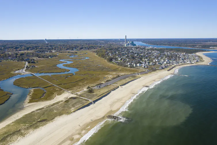 A view across the coast to a town and a narrow wetland area with a river snaking through it.