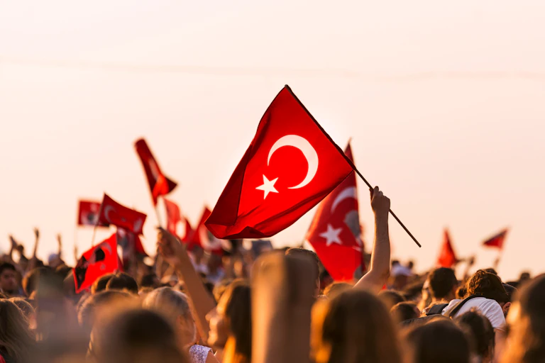A crowd of people holding Turkish flags above their heads.