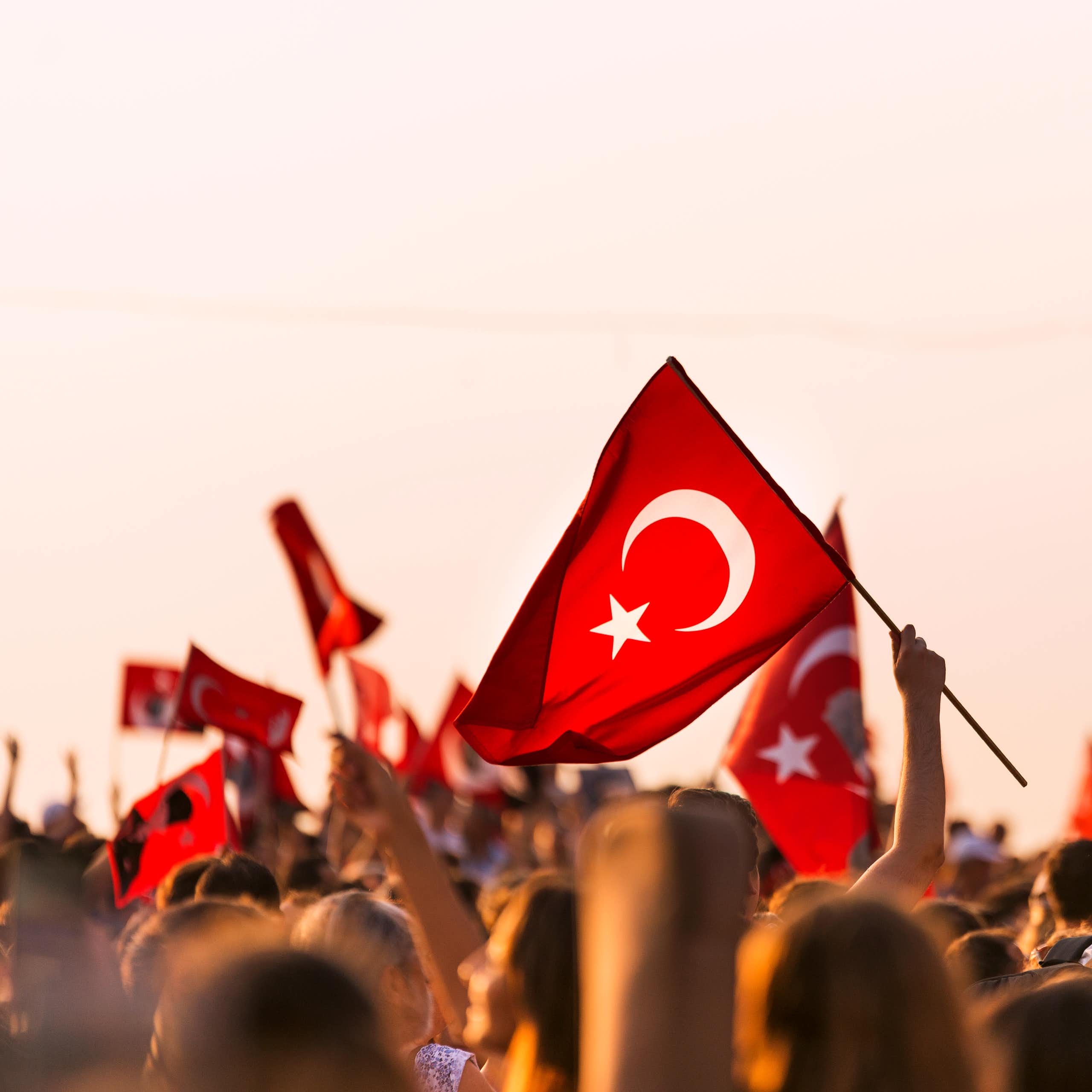 A crowd of people holding Turkish flags above their heads.