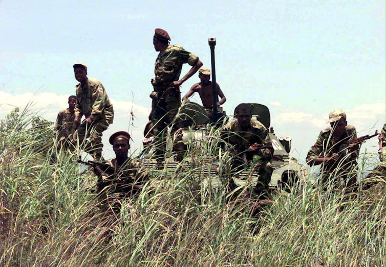 An image of Angolan soldiers standing on a tank holding their weapons.