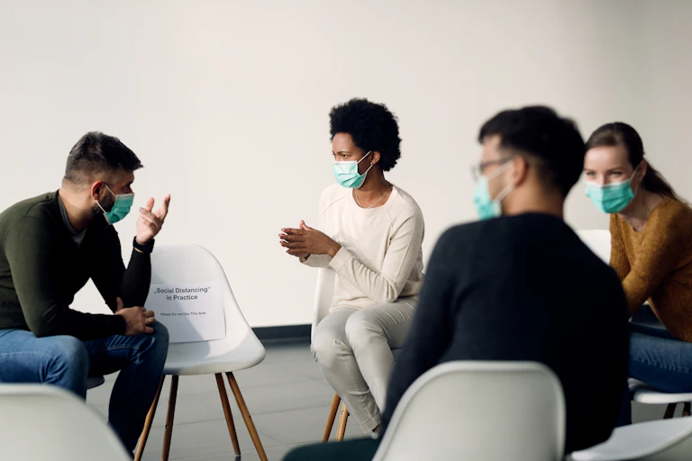 A group of people wearing face masks in a socially distanced circle