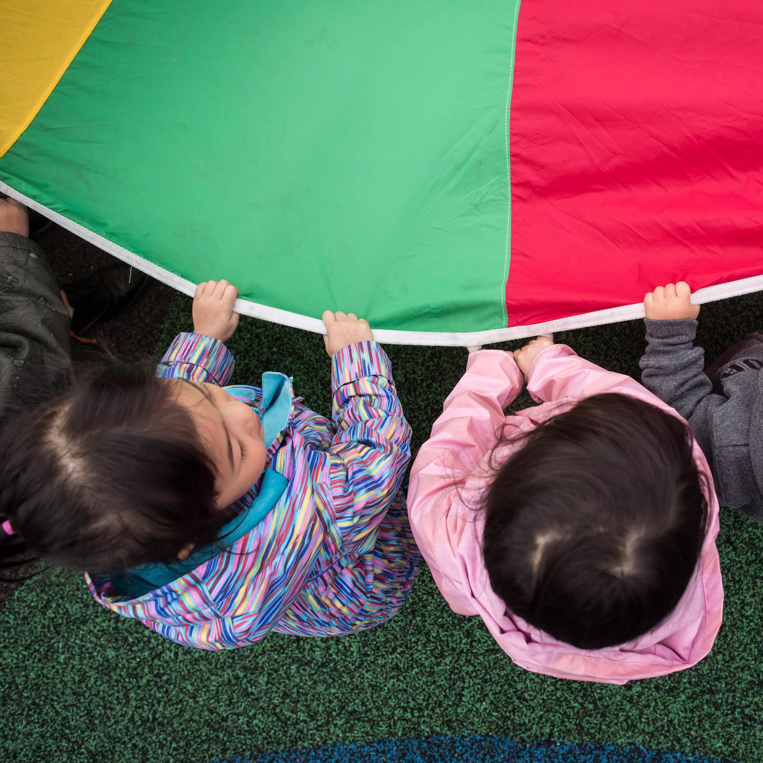 Little kids play with a parachute