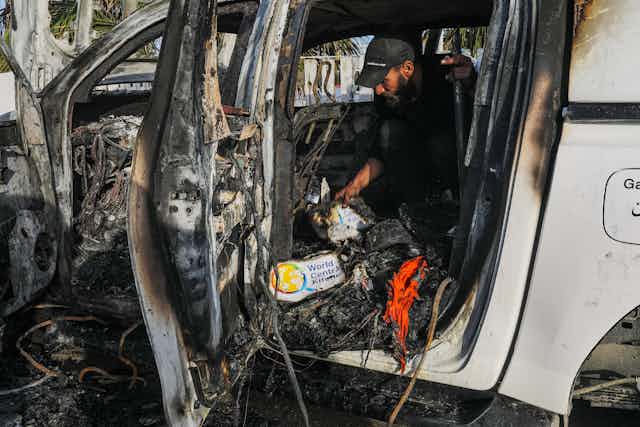 A blown up, blackened white car with the logo of World Central Kitchen in the wreckage