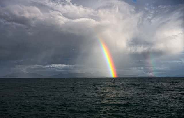 Double rainbows amid stormy clouds over the dark ocean
