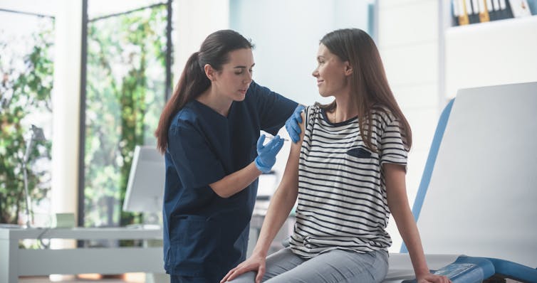 A woman receives a vaccination from a female health-care worker.