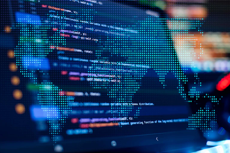 Photo showing pixelated map of the world superimposed on computer screen showing lines of code.