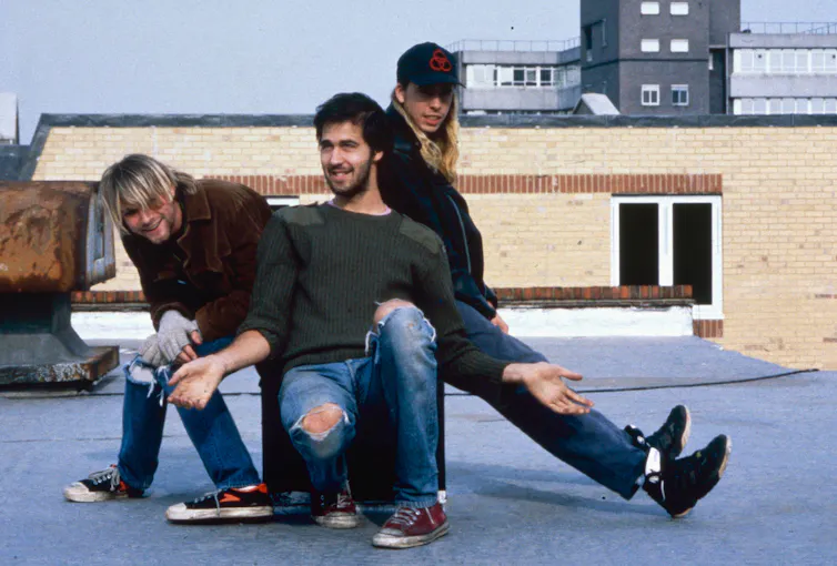 Three members of Nirvana sat on a roof.