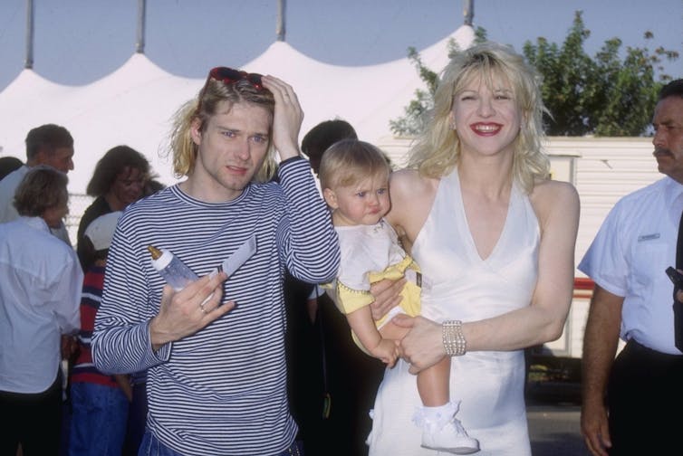 Kobain with Courtney Love carrying their daughter, Frances Bean. He holds a baby bottle.