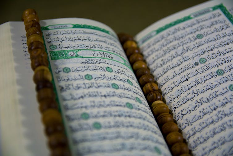 A close-up of an open Quran with a tasbeeh on it.