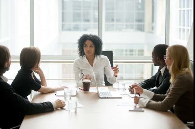 A Black woman leading a corporate team meeting.