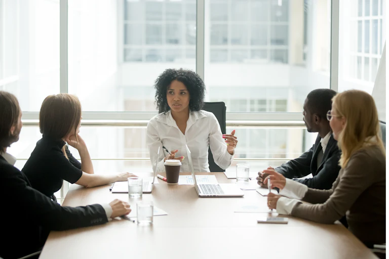 A Black woman leading a corporate team meeting.