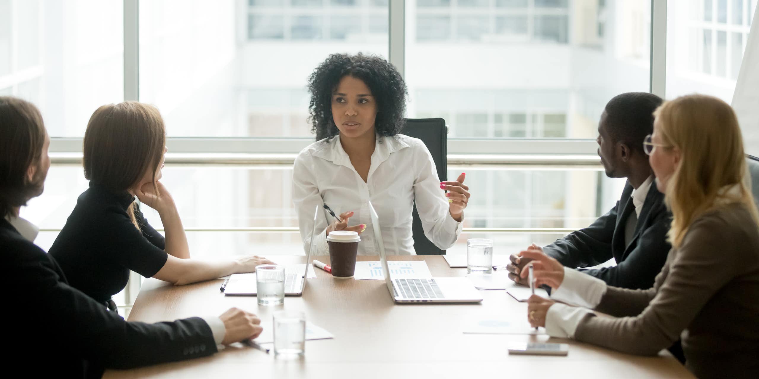 A Black woman leading a corporate team meeting.