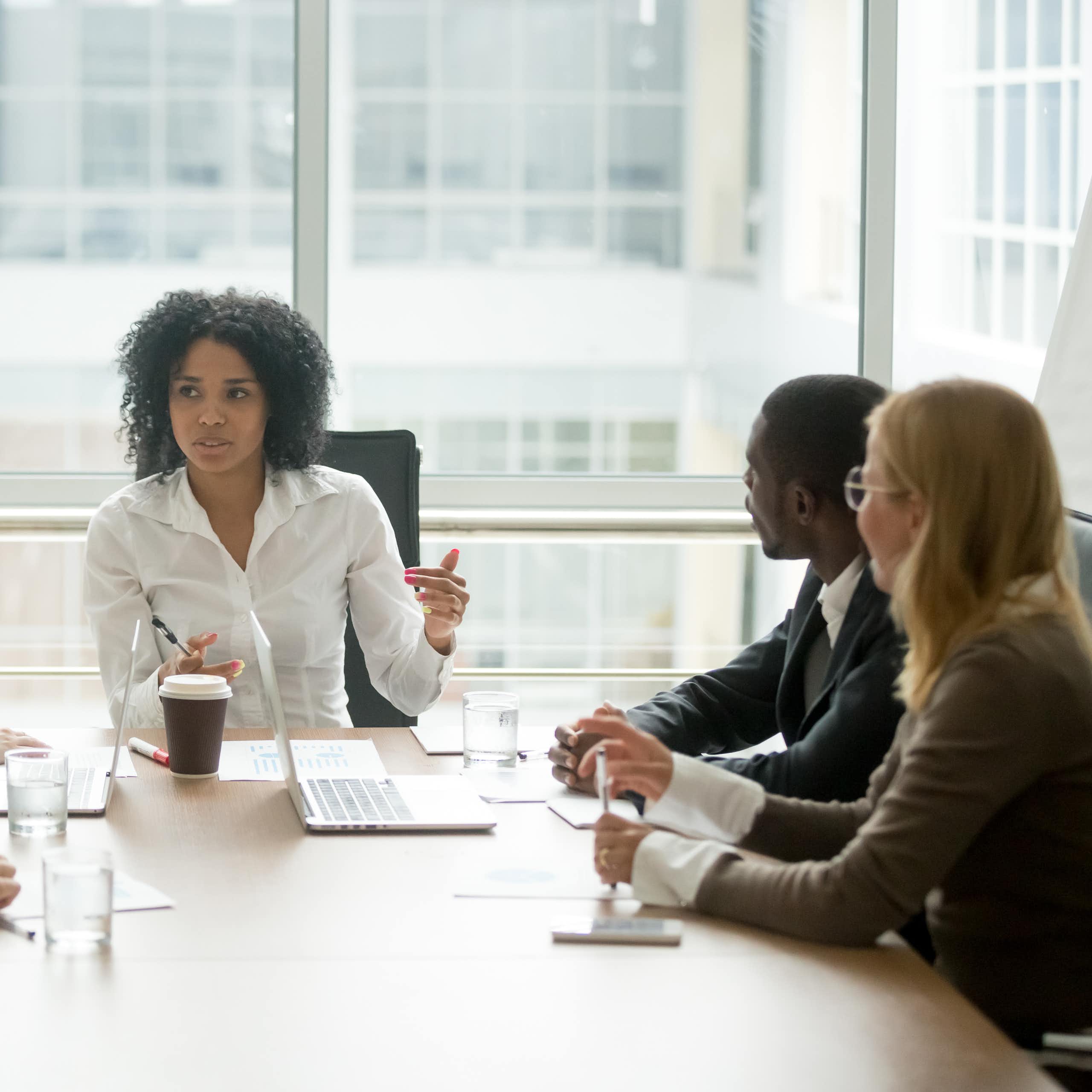 A Black woman leading a corporate team meeting.