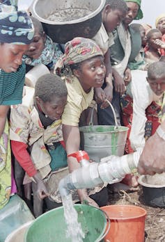 Women gather with pots as someone distributes water.