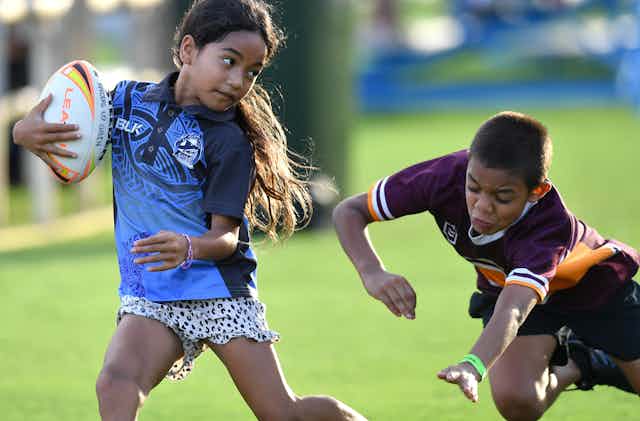 Two children having fun playing rugby league