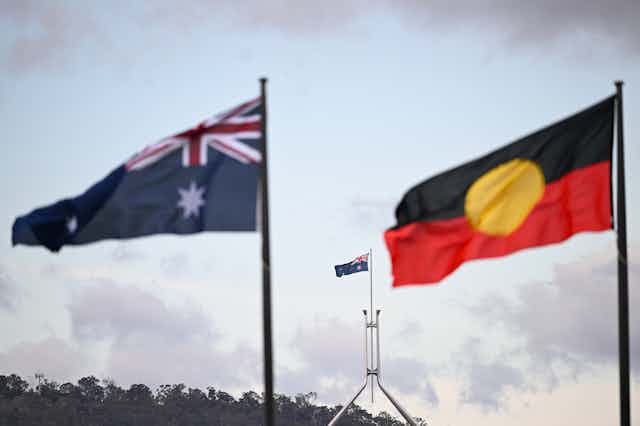 The Australian and Aboriginal flag are shown flying in the wind.