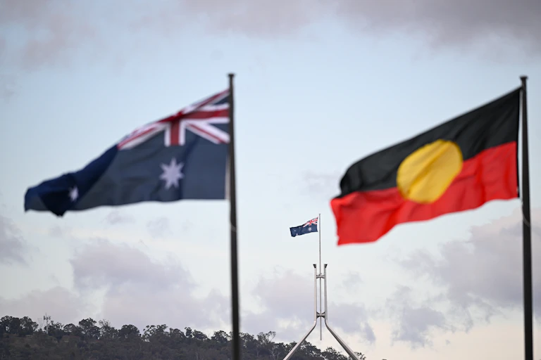 The Australian and Aboriginal flag are shown flying in the wind.
