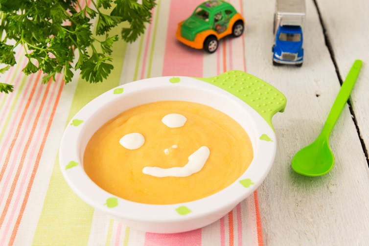 Lentil or pumpkin soup in a bowl with a smily face dolloped in cream or yoghurt