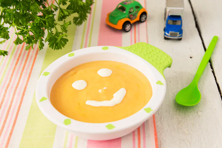 Lentil or pumpkin soup in a bowl with a smily face dolloped in cream or yoghurt