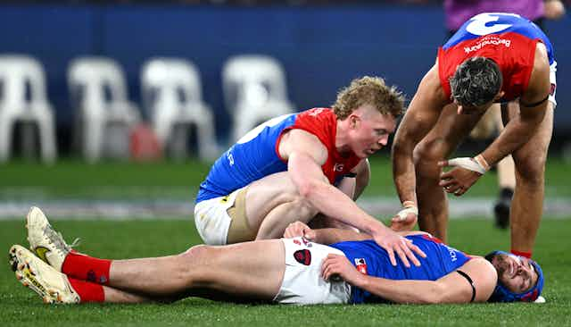 AFL player Angus Brayshaw lays concussed on the ground