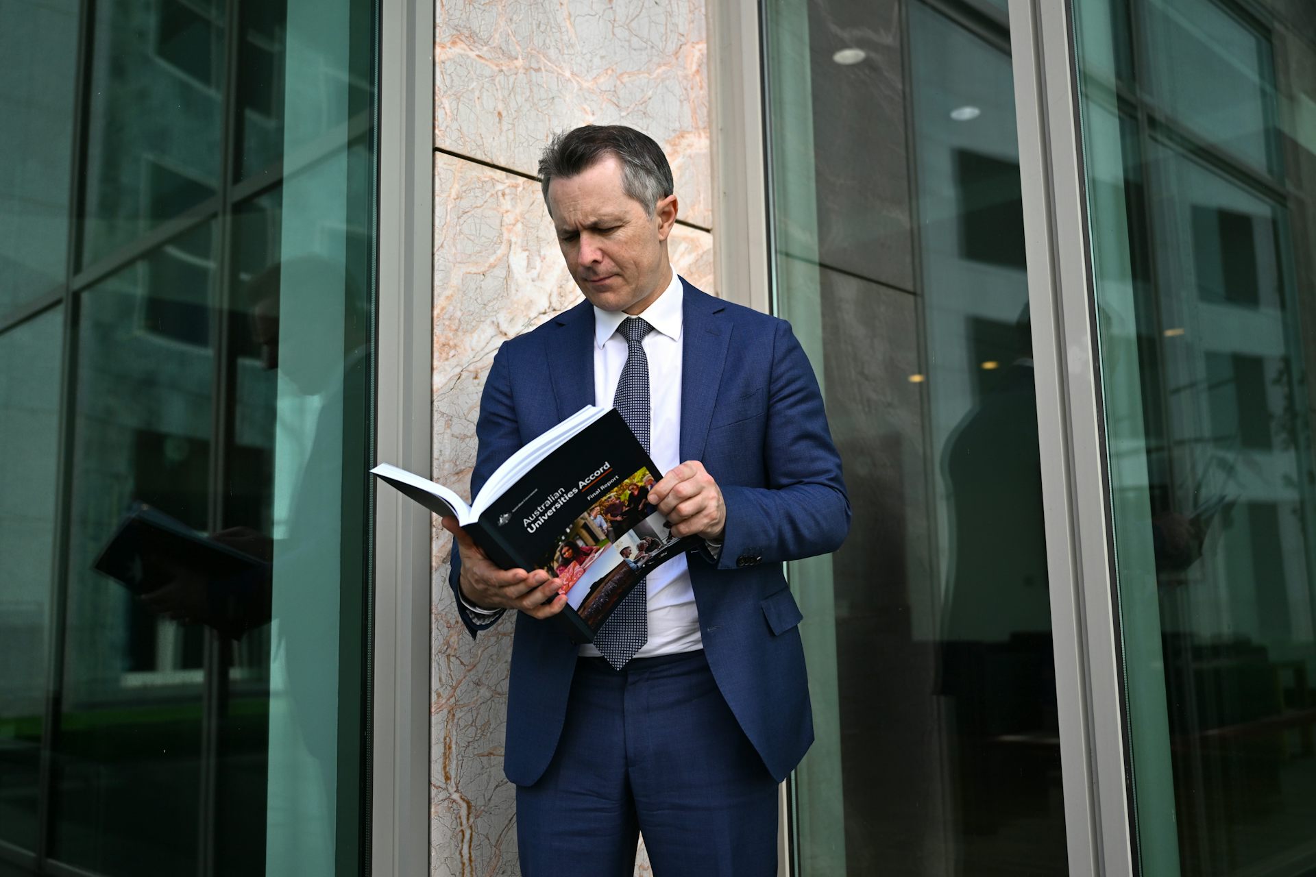 Education Minister Jason Clare looks at a copy of the Universities Accord final report.