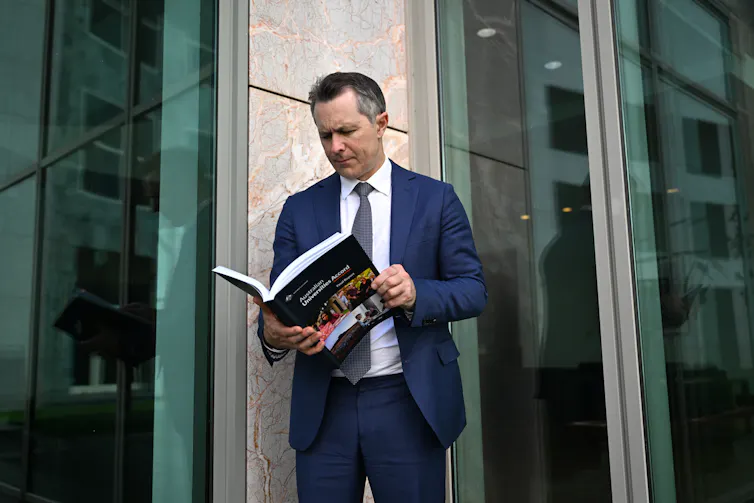 Education Minister Jason Clare looks at a copy of the Universities Accord final report.