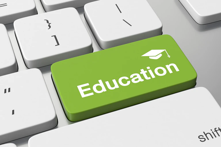 An illustration of a keyboard with very large keys. The word Education below a mortarboard hat is written on one key, which is an olive green colour