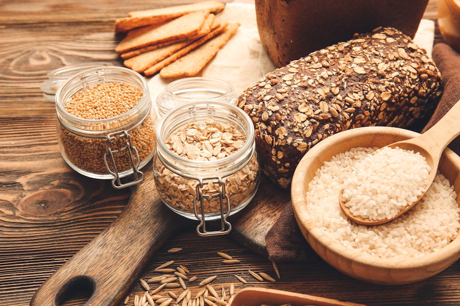 Jars of whole grains and a loaf of whole grain bread. 