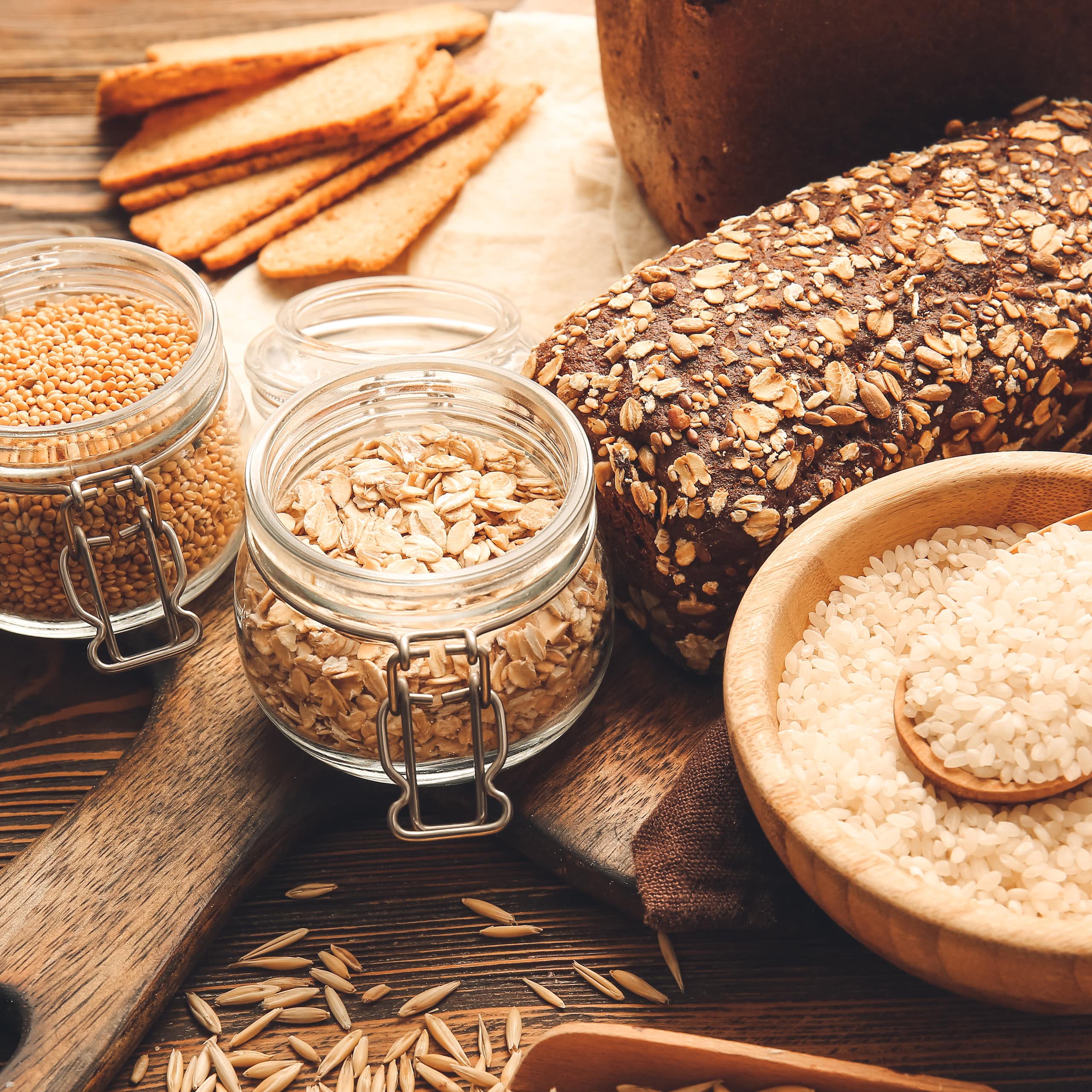Jars of whole grains and a loaf of whole grain bread. 