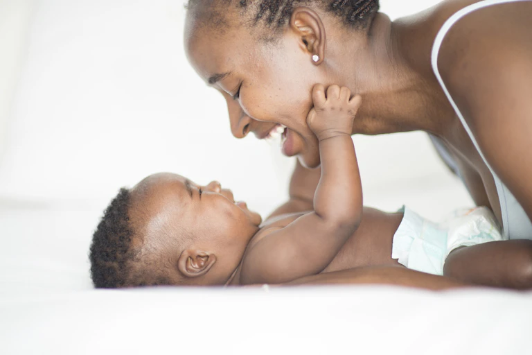 Woman smiling at baby who is grasping her face.