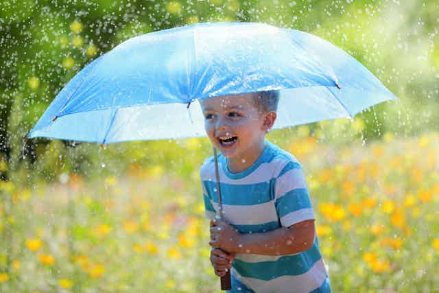 Boy holds umbrella in rain