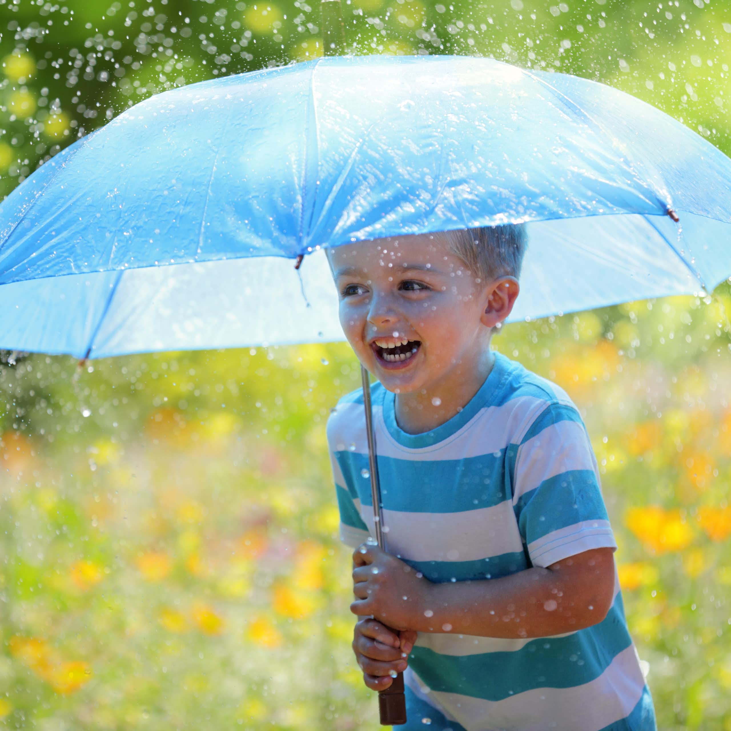 Boy holds umbrella in rain