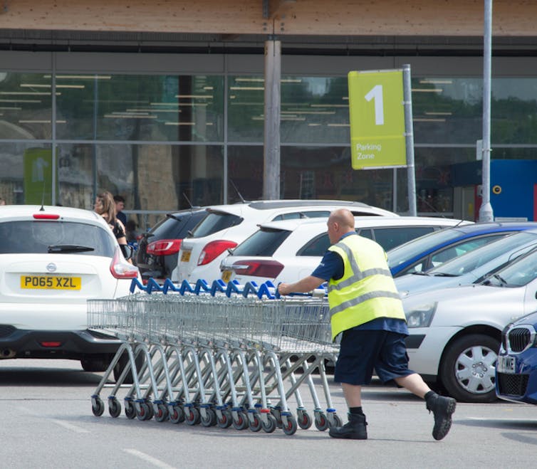 Supermarket worker pushing a trolley