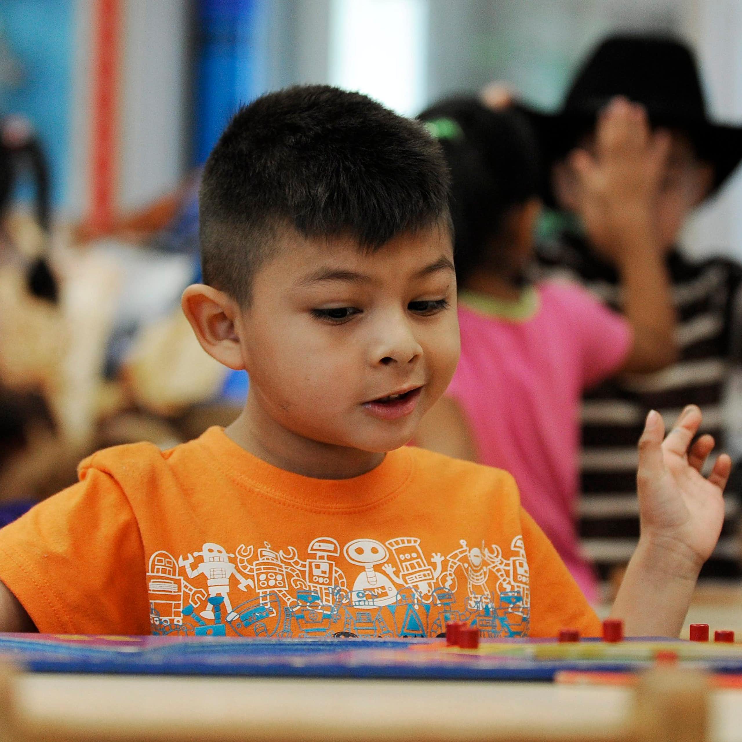 A child looking absorbed in figuring out a puzzle with a snamm smile on his face.