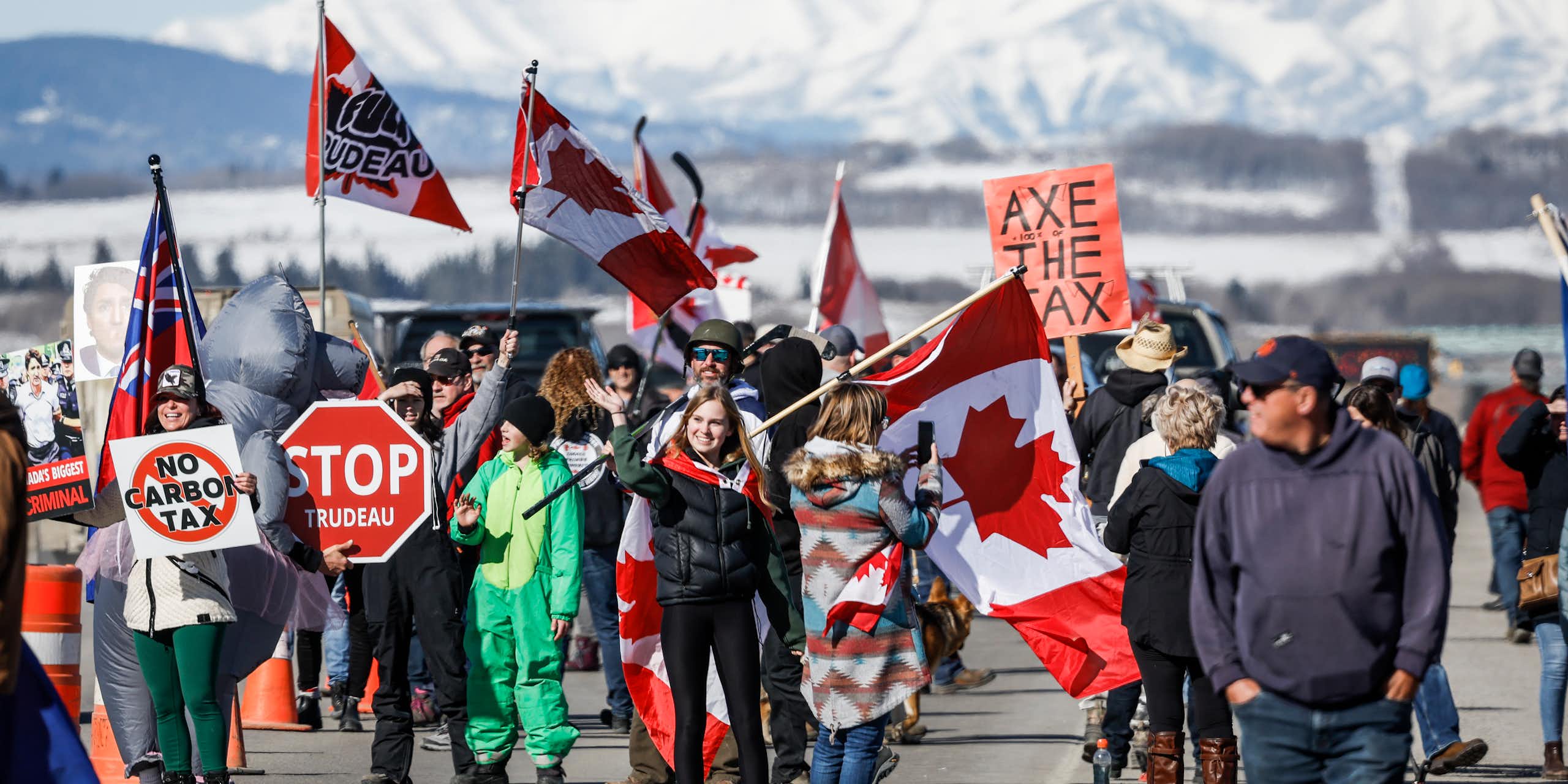 A group of people holding signs and flags walk down the road.