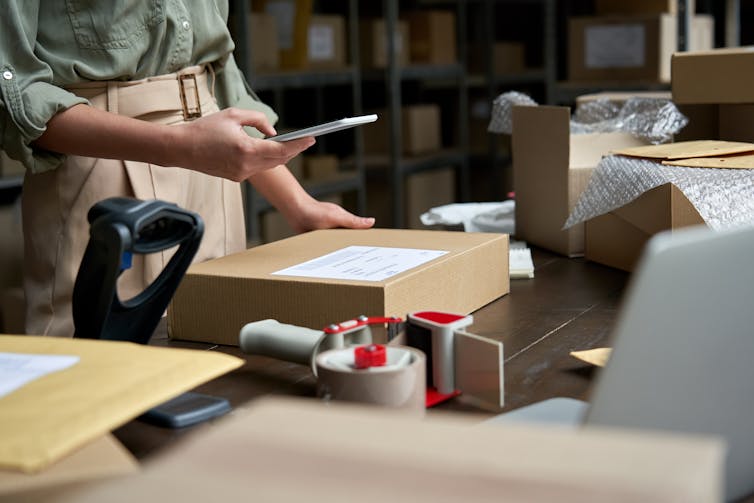 Close-up of a warehouse worker using a mobile app on his smartphone to scan labels on cardboard boxes