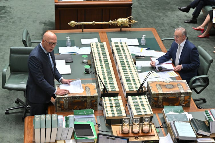 Two men sit opposite each other in the house of representatives