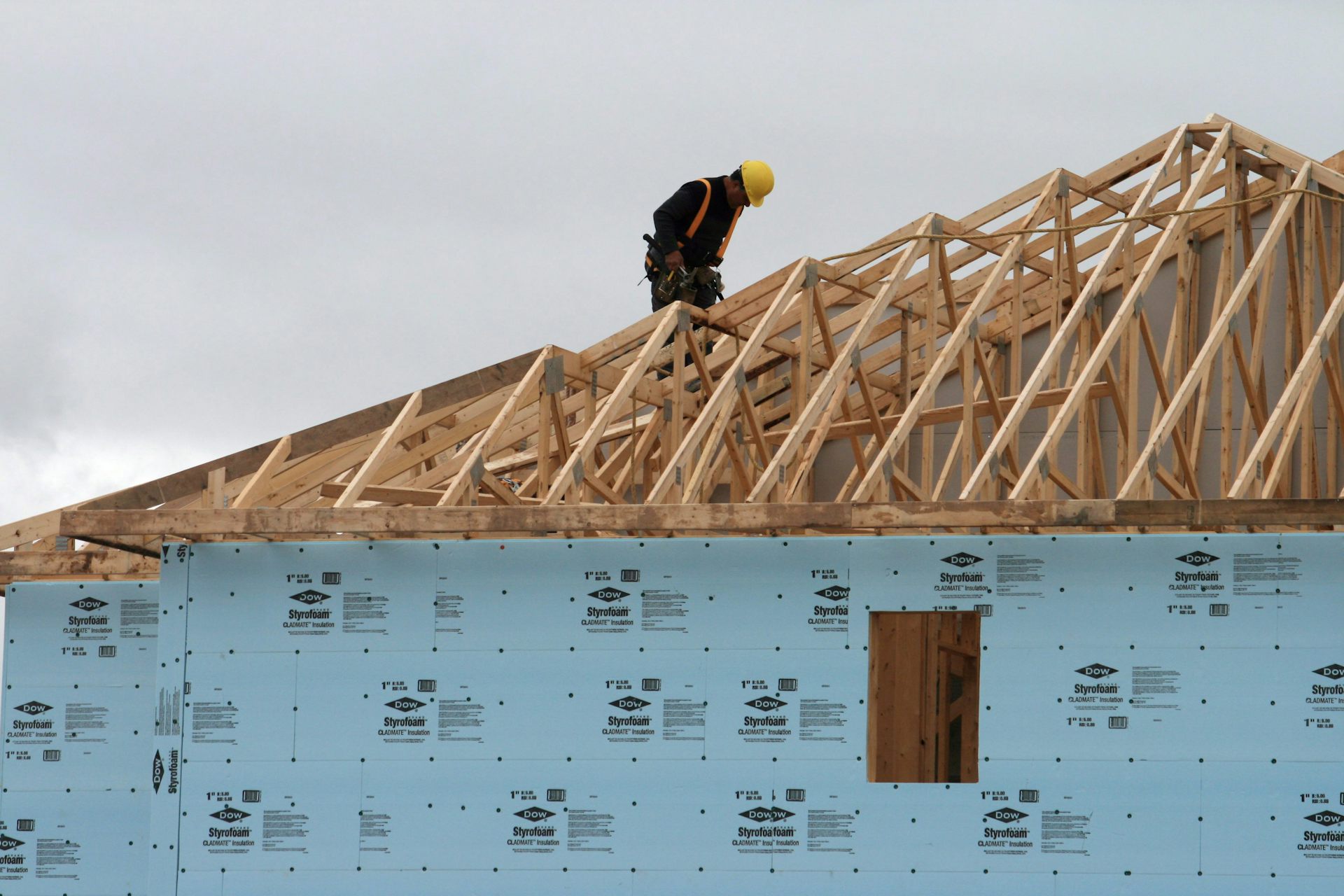 A construction worker works on a roof of a house being constructed.