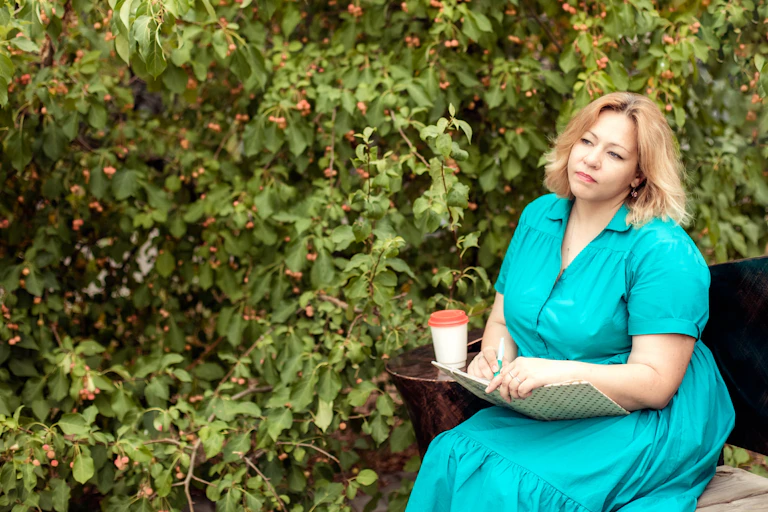 Woman looks unhappy sitting on park bench with notepad