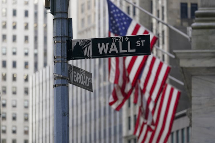 The American flag hangs from a building in Wall St.