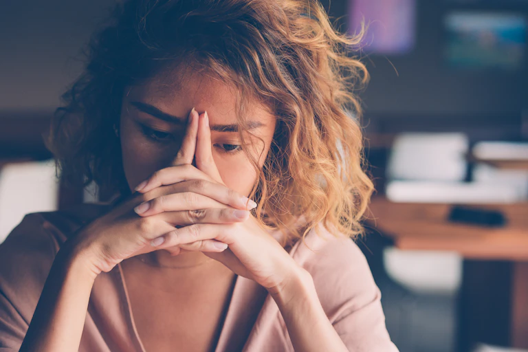 woman holds hands at face and looks worries
