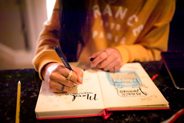 Young person draws in notebook