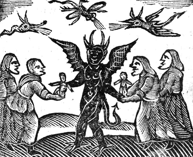 A very old depiction of a Devil with horns and a tail offering dolls to a group of surrounding people. 