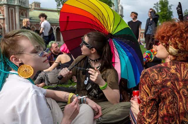 Young people gather in a park in Moscow wearing rainbow and other LGBT symbols