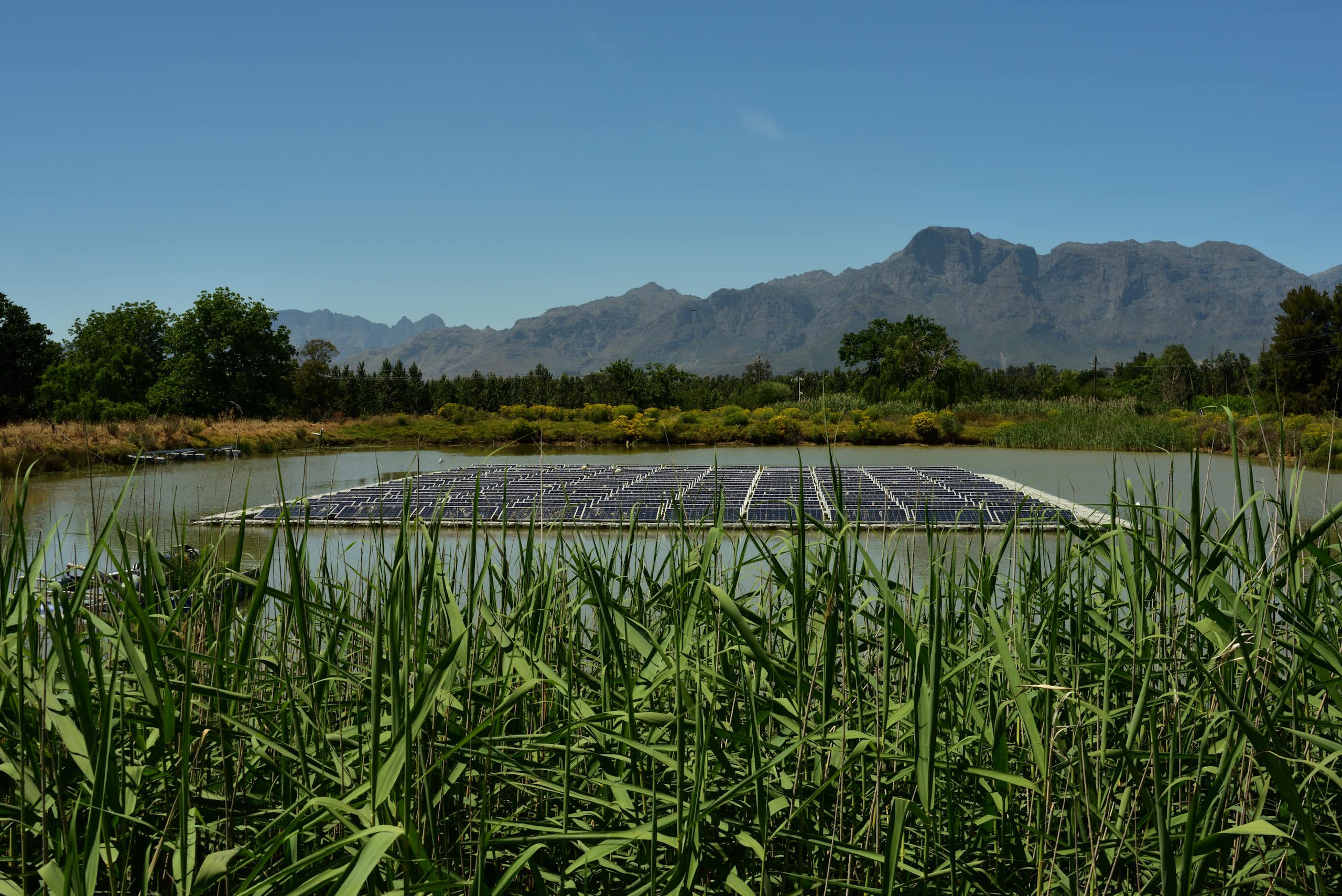 Landscape showing a large solar panel on the surface of a rural dam
