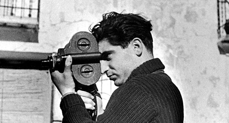 Un hombre con una cámara de cine en una fotografía en blanco y negro.