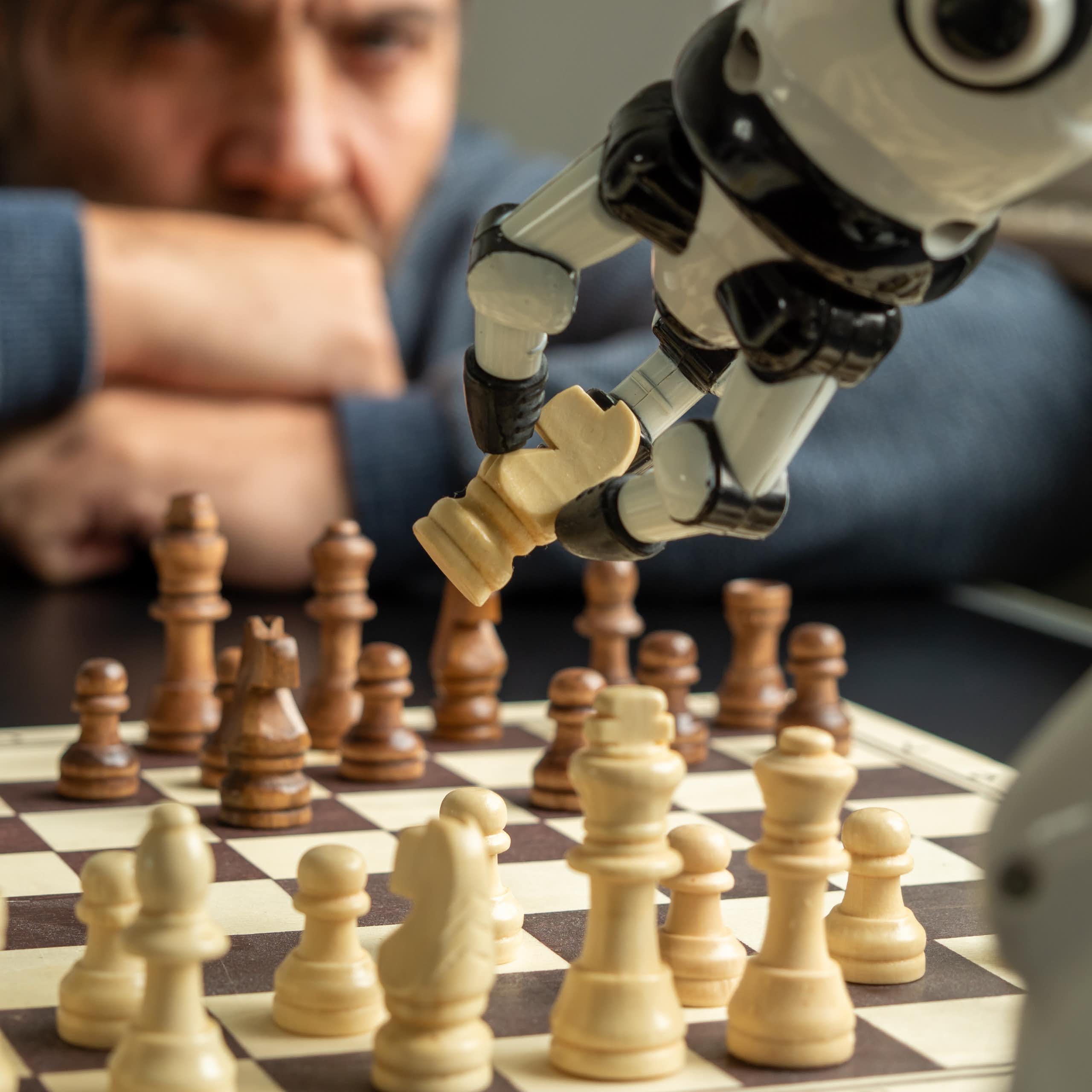 Un bras robotisé saisit une pièce d'échecs dans une partie contre un humain
