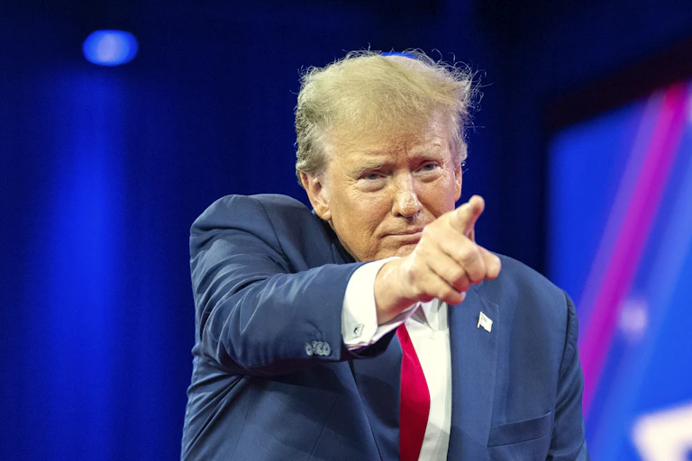 A man in a business suit points into a crowd.