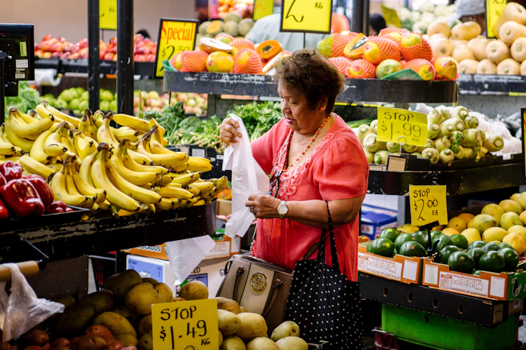 Woman standing in food aisle at supermarket holding a plastic bag